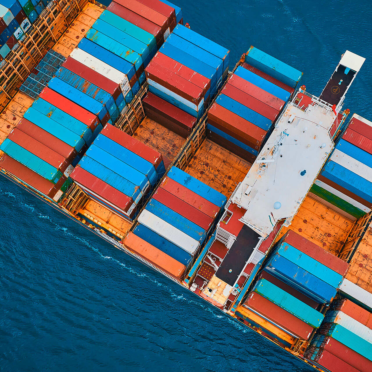 An aerial view of a large container ship heavily loaded with colorful shipping containers.